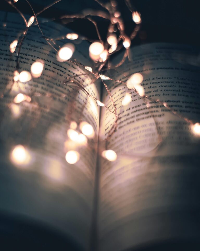 An open book illuminated by delicate string lights, creating a warm and serene ambiance.